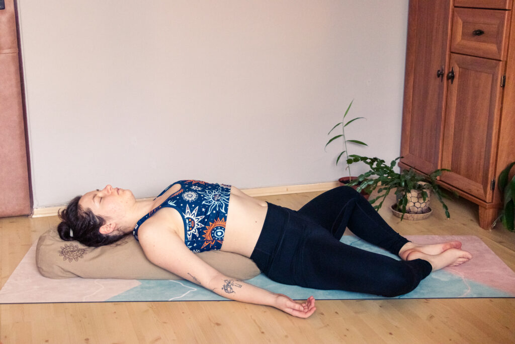 a yogini in the reclined goddess pose during a restorative yoga class